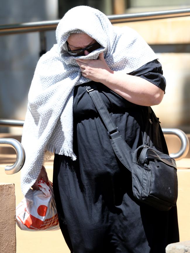 Helena Heaft covers her face as she leaves the Adelaide Magistrates Court. Picture: AAP / Kelly Barnes