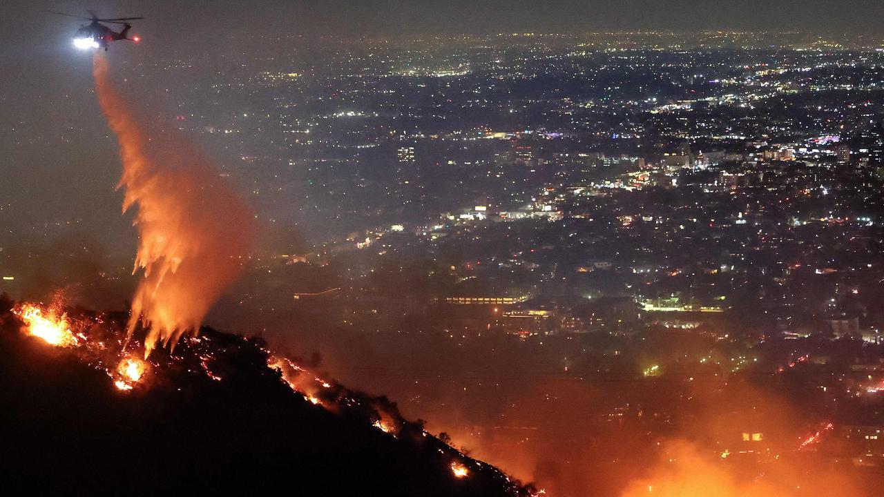 A firefighting helicopter drops water as the Sunset Fire burns in the Hollywood Hills. Picture: Getty Images via AFP