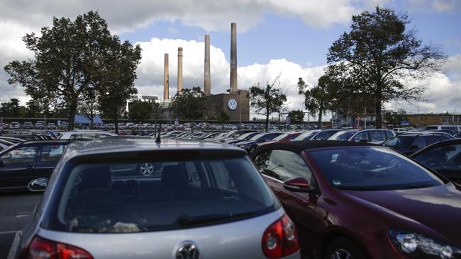 A car parking lot is packed with cars in front of the power plant.