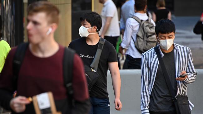 People make their way through streets of the central business district of Sydney with face masks on. Picture: Saeed Khan