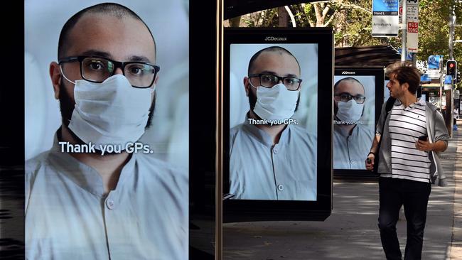 A man walks past a Sydney bus stop where advertising boards displaying thankyou messages for health workers. Picture: AAP