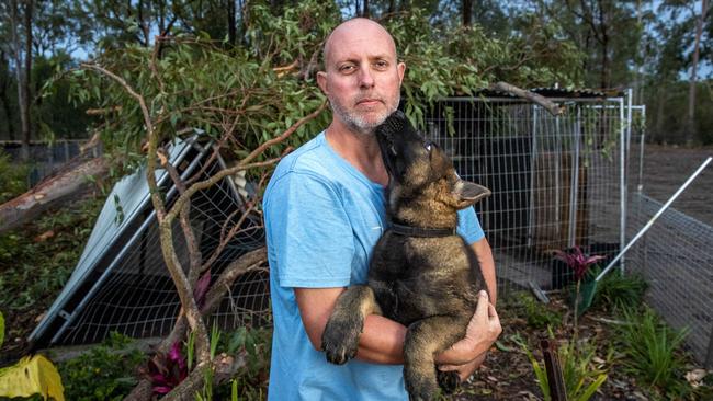 Matt Stieler with Gas the puppy, whose kennel was crushed by a fallen tree in Karalee. Mr Stieler’s neighbour was seriously hurt by a fallen tree. Picture: Richard Walker