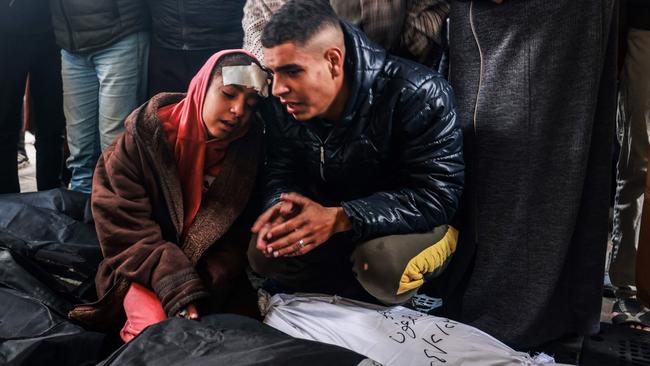 An injured girl and man mourn over the bodies of relatives killed in overnight Israeli bombardment, at the Al-Najjar hospital in Rafah. Picture: AFP