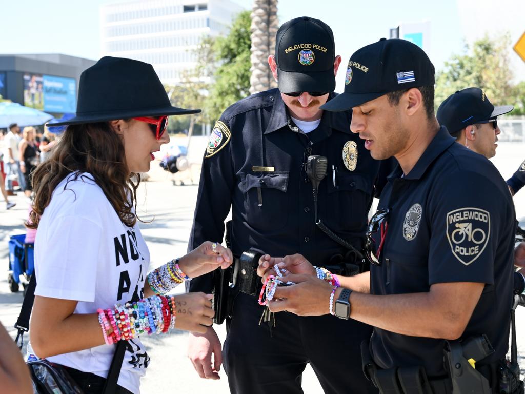 A fan shows their friendship bracelets to Inglewood police officers before the show in Los Angeles. Picture: Michael Buckner/Variety via Getty Images