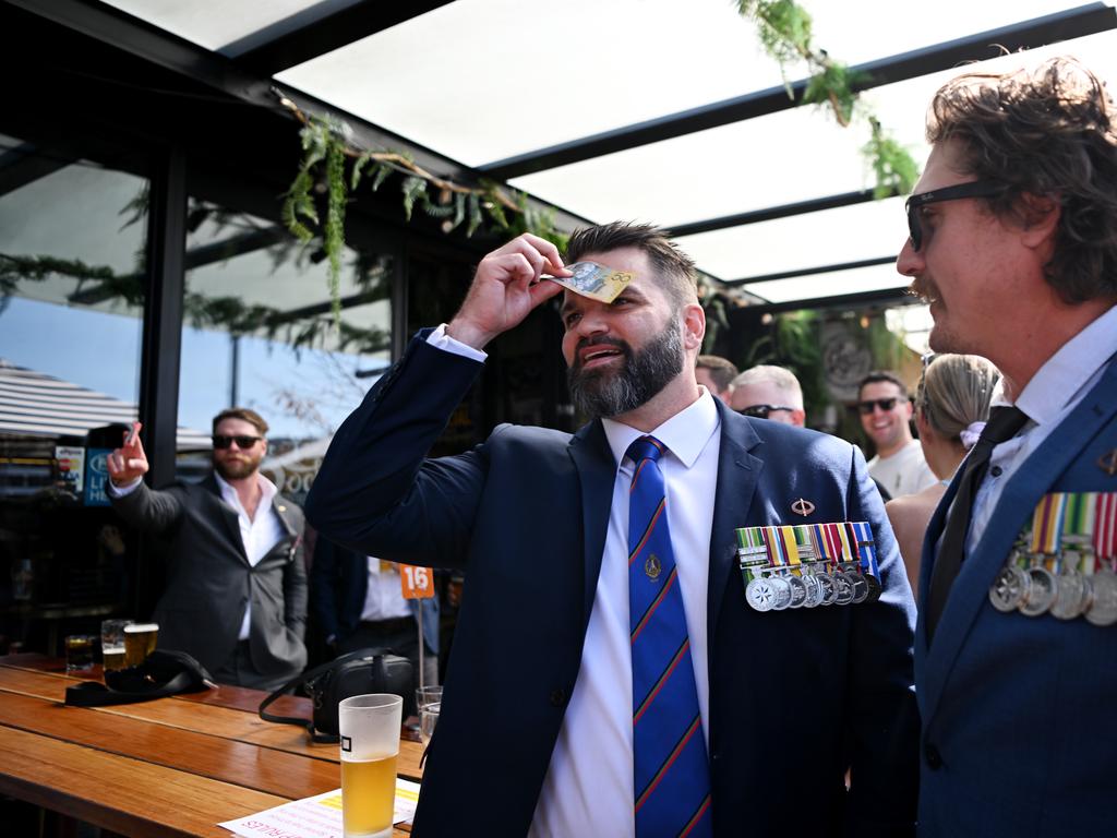 One veteran displays his medals as he plays a game of Two Up. (Photo by Tracey Nearmy/Getty Images)