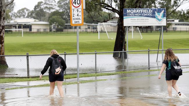 Students wade through floodwaters outside Morayfield State High School. Picture: Josh Woning