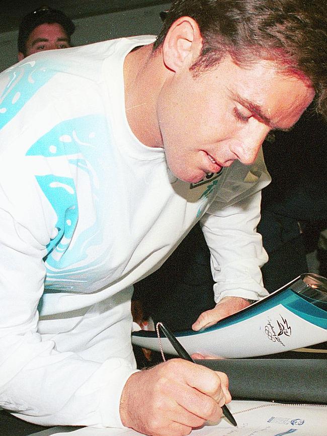 Brad Fittler signs the book after his torch leg at Parramatta Park. Picture: Simon Dean