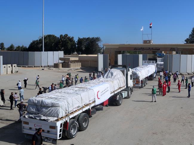 People on the Egyptian side of the Rafah border crossing watch as a convoy of trucks carrying humanitarian aid crosses to the Gaza Strip on October 21, 2023. Picture: AFP.