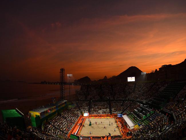 Spectators watch the men's beach volleyball qualifying match between the Netherlands and Russia as the sun sets over Copacabana's Beach Volley Arena in Rio de Janeiro on August 6, 2016, during the Rio 2016 Olympic Games. / AFP PHOTO / Leon NEAL