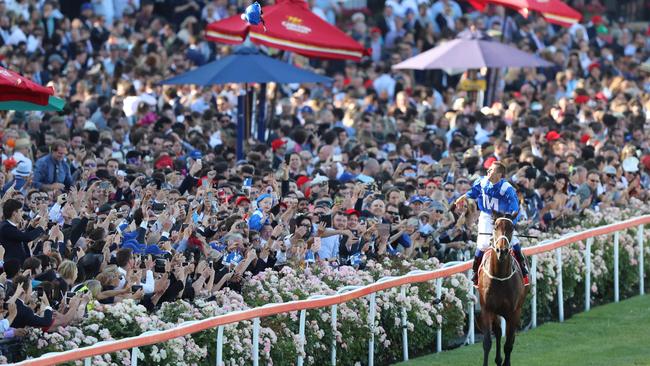 Hugh Bowman throws hi skull cap into the crowd after Winx equalled Kingston Town’s record of three Cox Plates last year. Picture: Alex Coppel