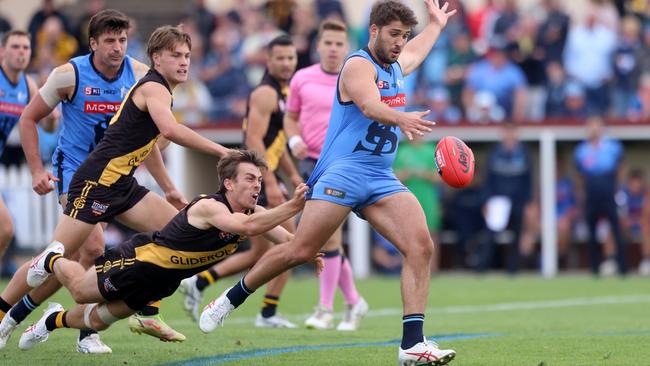 Sturt’s James Battersby gets a kick away under pressure from Glenelg’s Luke Partington in the Round 1 encounter at Unley Oval. Picture: Cory Sutton