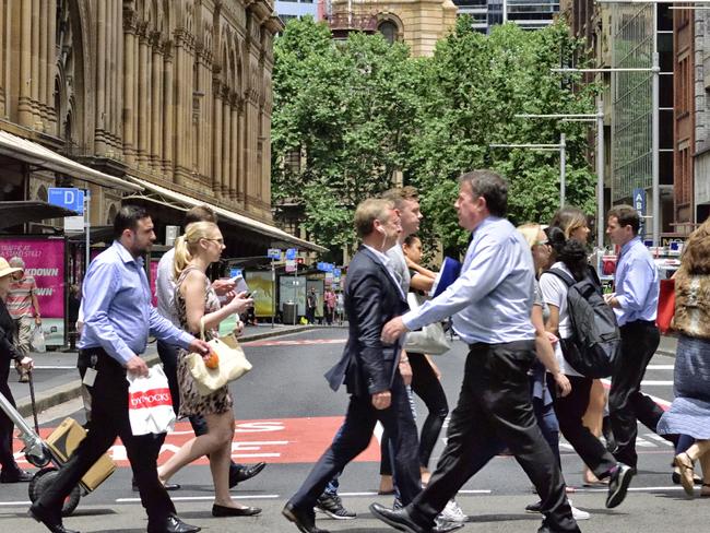 Sydney, Australia - November 12, 2015: People crowd crossing street in central Sydney. Landmark in background, shopping center to the left.