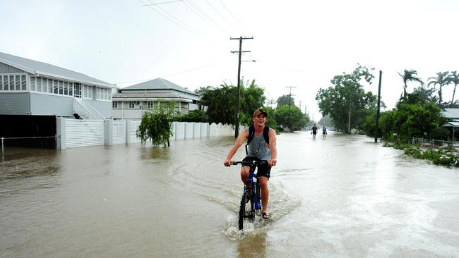 Townsville floods. A man rides his bike in Clayton Street, Hermit Park. Picture: Evan Morgan