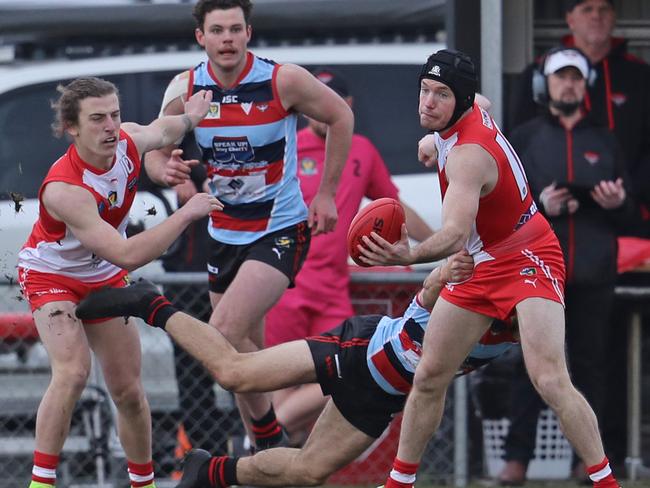 Clarence’s Brady Jones gets a handball away under pressure from his Lauderdale opponent. Picture: LUKE BOWDEN