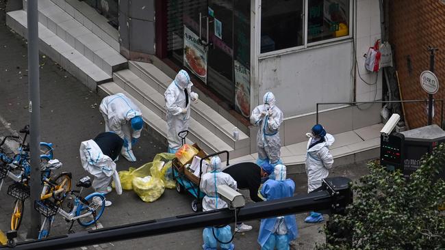 Workers take off their protective gear next to the entrance of a neighbourhood during the second stage of a pandemic lockdown in Jing' an district in Shanghai. Picture: AFP