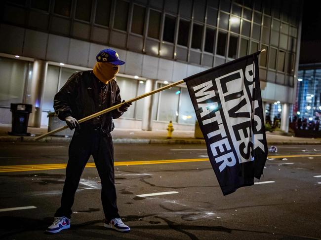A protester wearing a Black Panther jacket and holding a "Black Lives Matter" flag faces off with riot police in Rochester, New York, on September 5, 2020, on the fourth night of protest following the release of video showing the death of Daniel Prude. - Prude, a 41-year-old African American who had mental health issues, died of asphyxiation after police arrested him on March 23, 2020, in Rochester. (Photo by Maranie R. STAAB / AFP)