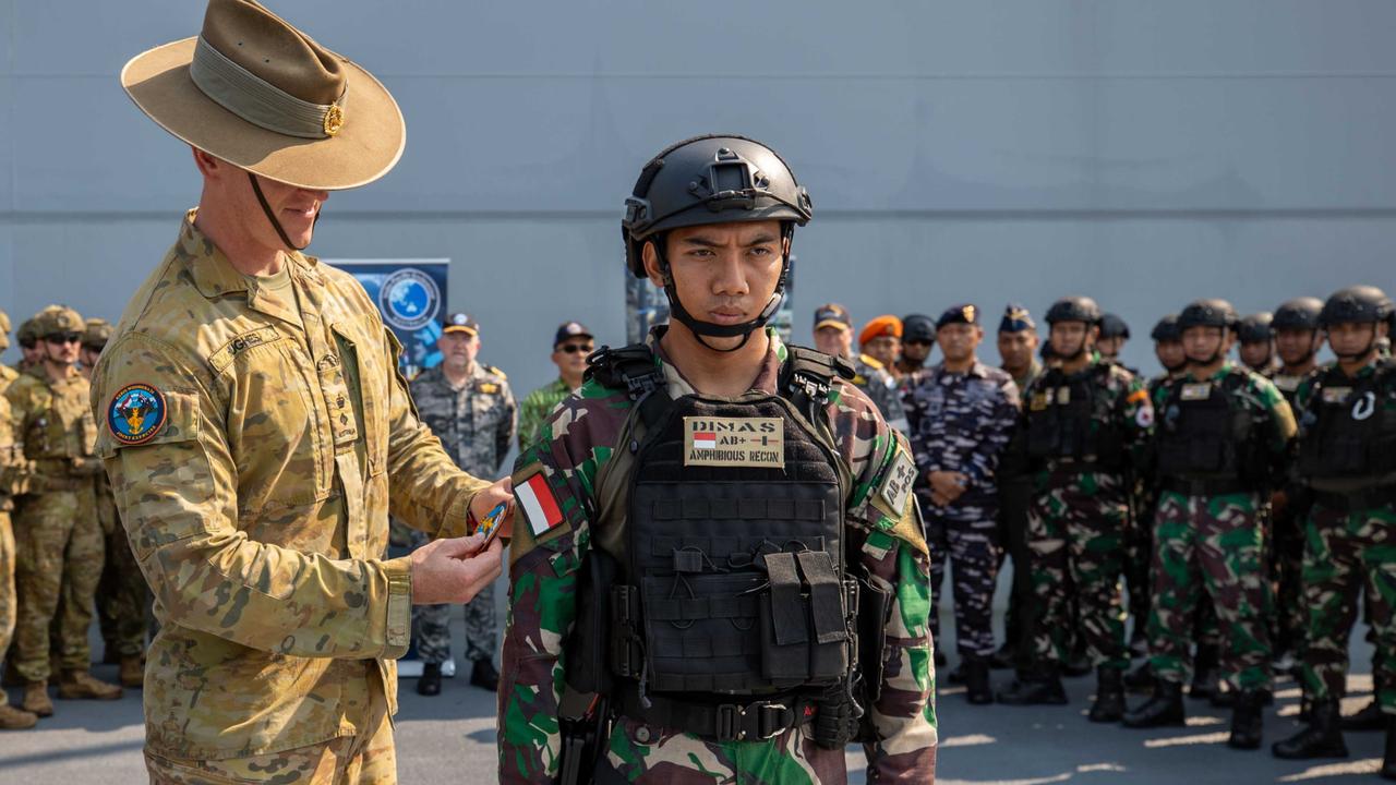 Lieutenant Colonel Brent Hughes, Commanding Officer of 1st Battalion, the Royal Australian Regiment, places a patch on a soldier from the Indonesian National Armed Forces (TNI) during the media launch of Exercise KERIS WOOMERA on HMAS Adelaide at Larrakeyah Defence Precinct, Darwin, NT. PHOTO: CPL Janet Pan