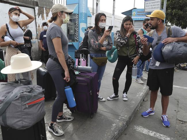 Tourists from the United States wait outside the closed Jorge Chavez International Airport for a member of the U.S. Embassy to escort them to a flight that will fly them back to the U.S., in Callao Peru, Friday, March 20, 2020, on the fifth day of a state of emergency decreed by the government to prevent the spread of the new coronavirus.  (AP Photo/Martin Mejia)