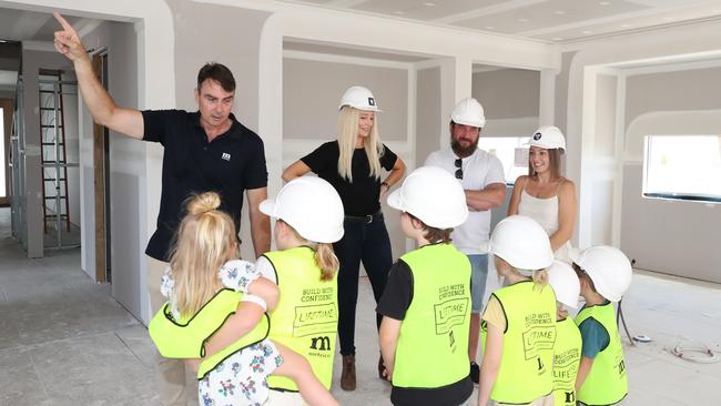 Greg Heaton from Metricon Homes and organiser Tamika Smith show Danielle and Rhys Carroll and the children the new home being built for them by builders and volunteers. Picture Glenn Hampson