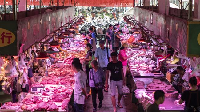 Customers walk past tables laden with pork at the Dancun Market in Nanning in China’s Guangxi province in September last year. Picture: Bloomberg