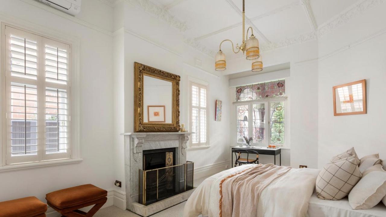 This elegant bedroom features high ceilings, decorative cornices and a working fireplace framed by original marble.