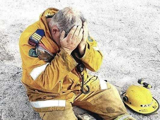 Aaron Cox, a Ballandean rural firefighter, sits exhausted and emotional after his crew managed to save property from one ferocious fire.