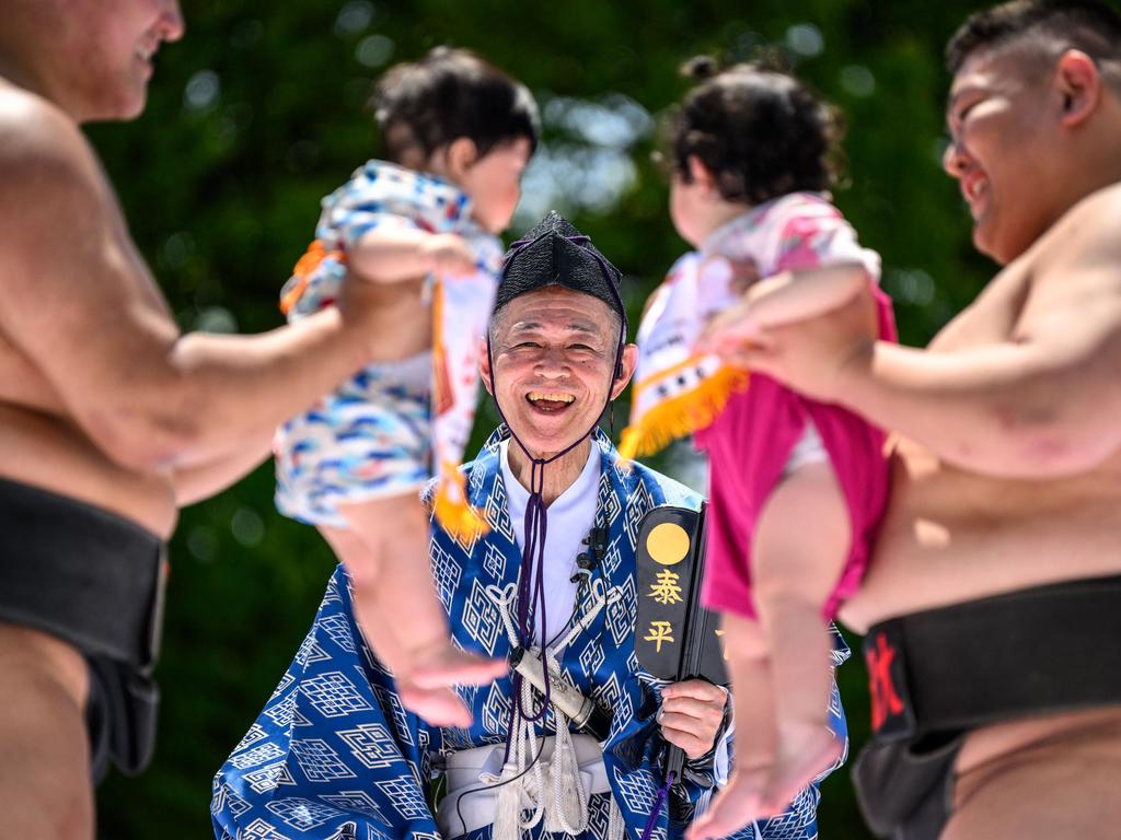 Sumo wrestlers hold children during a “crying baby sumo” match at Sensoji Temple in Tokyo, where it’s believed that the wrestlers help babies cry out wishes for good health. Picture: Philip Fong/AFP