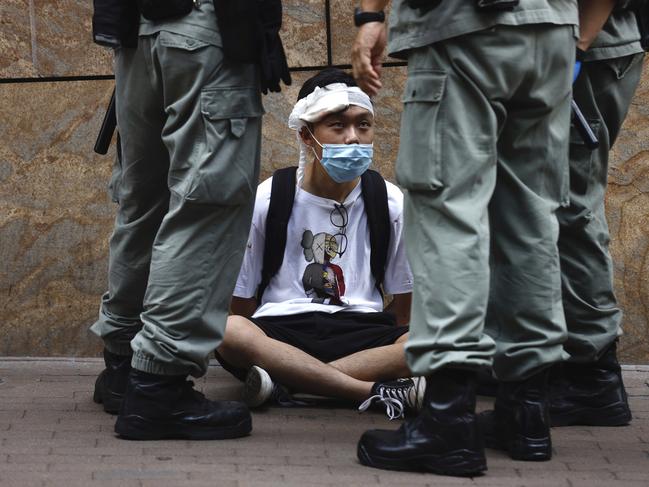 Riot police guard a protester as a second reading of a controversial national anthem law takes place in Central district, Hong Kong, Wednesday, May 27, 2020. Hong Kong police massed outside the legislature complex Wednesday, ahead of debate on a bill that would criminalize abuse of the Chinese national anthem in the semi-autonomous city. (AP Photo/Kin Cheung)