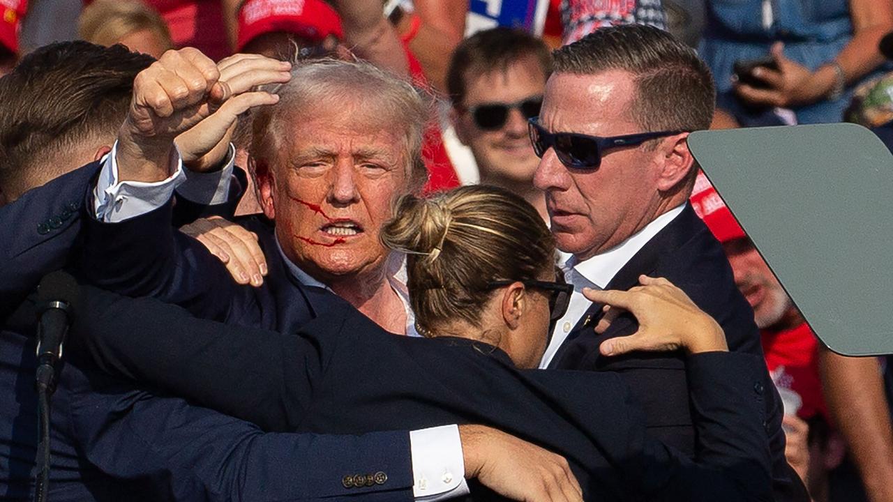 US Republican candidate Donald Trump is seen with blood on his face surrounded by secret service agents as he is taken off the stage at a campaign event at Butler Farm Show. Picture: AFP