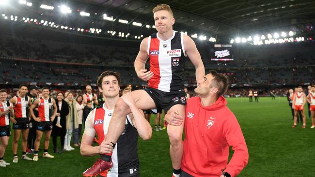 Josh P. Kennedy of the Swans and Jack Steele of the Saints chair Dan Hannebery of the Saints off the field. Photo by Morgan Hancock/AFL Photos/via Getty Images