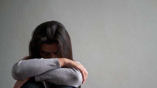 Depressed woman sitting on a chair in dark room at home. Lonly , sad, emotion concept.