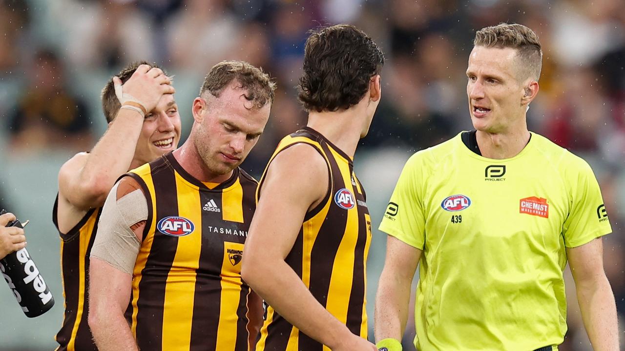 Tom Mitchell of the Hawks speaks with AFL Field Umpire, Hayden Gavine after a 50 metre penalty was awarded to Geelong