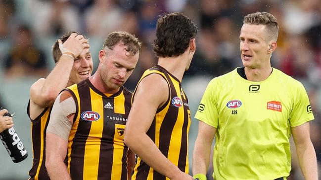 Tom Mitchell of the Hawks speaks with AFL Field Umpire, Hayden Gavine after a 50 metre penalty was awarded to Geelong