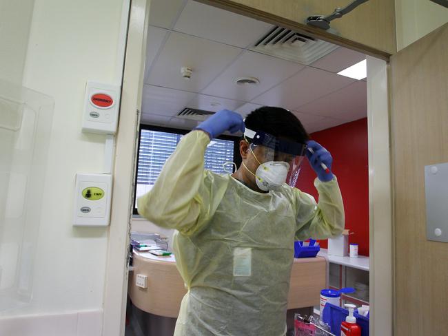 Registered Nurse Laxman Adhikari fits a face shield prior to conducting a nasal swab test in the clinical assessment room at Sydney’s St George Hospital. Picture: Getty Images