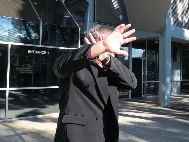 Former Juvenile Justice officer Peter Buckworth covers his face while leaving court. Picture: Richard Noone