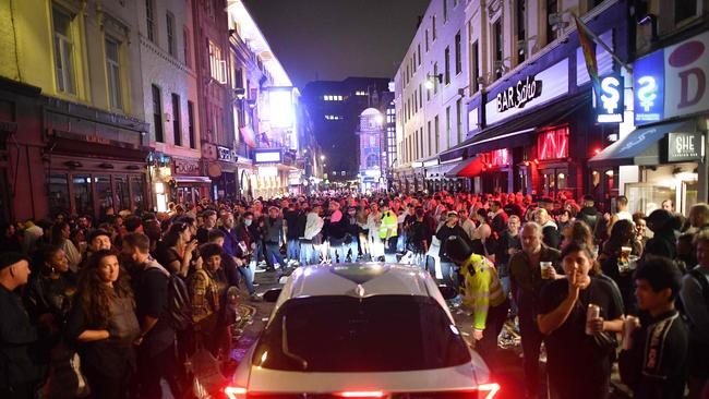 A car tries to drive along a street filled with revellers drinking in the Soho area of London. Picture: AFP