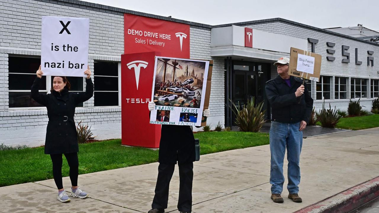 Activists hold signs while protesting outside a Tesla dealership in Los Angeles, California on March 14, 2025 amid a surge in nationwide protests against Elon Musk. Picture: Frederic J. BROWN / AFP