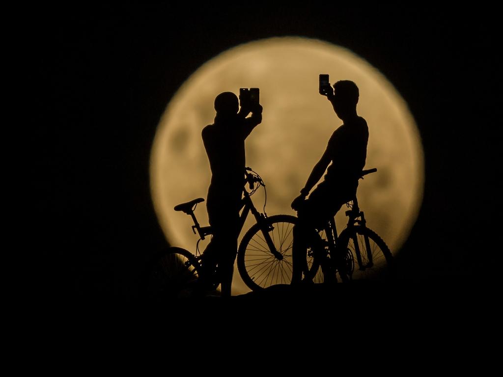 Photo Illustration showing people with bicycles taking photos of the Super moon on January 31, 2018 in Lancelin, Australia. Last seen from Australia in December 1983, a Super Blue Blood Moon is the result of three lunar phenomena happening all at once. Not only is it the second full moon in January, but the moon will also be close to its nearest point to Earth on its orbit, and be totally eclipsed by the Earth’s shadow. Picture: Paul Kane/ Getty