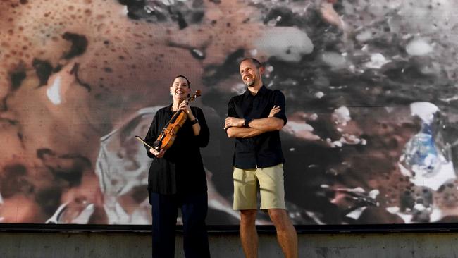 Adelaide Symphony Orchestra violinist Julia Brittain and artist Michael Kutschbach with his work titled “fuliguline” on the digital screen at the Adelaide Festival Centre. Picture: Tricia Watkinson