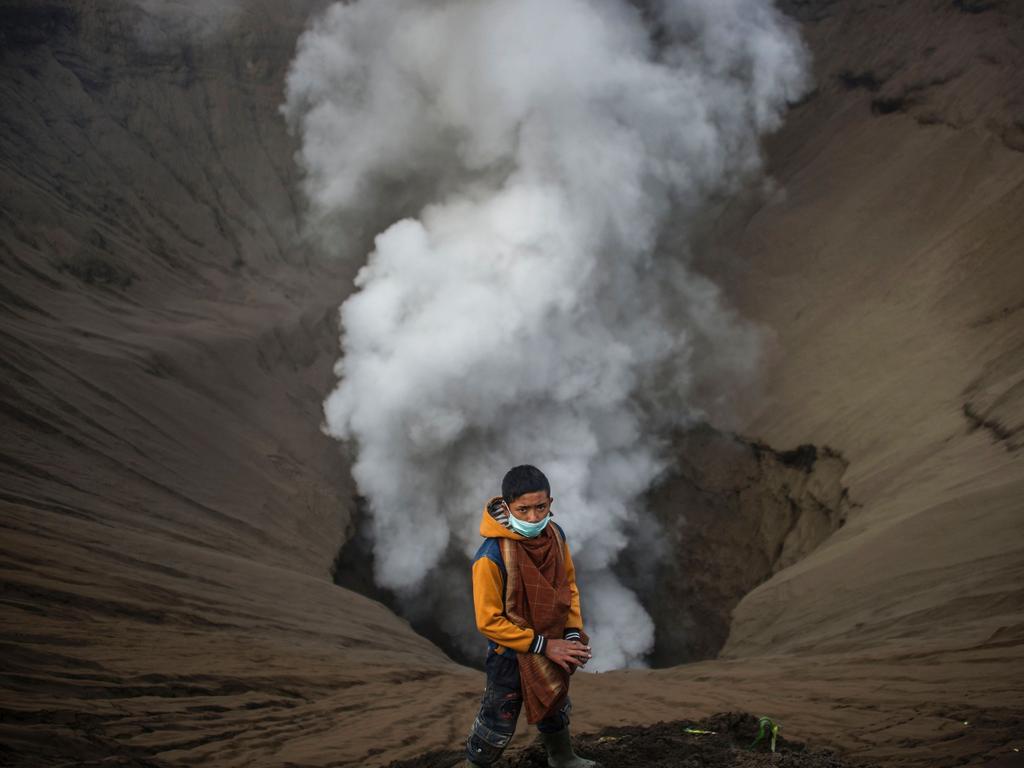 An Indonesian boy waits as he prepares to catch offerings released by Hindu devotees of the Tengger tribe during the Yadnya Kasada festival, on the crater of Mount Bromo in Probolinggo on July 21, 2016. During the annual Yadnya Kasada festival the Tenggerese climb Mount Bromo, an active volcano, and seek the blessing from the main deity Hyang Widi Wasa by presenting offerings of rice, fruit, livestock and other local produce. / AFP PHOTO / JUNI KRISWANTO