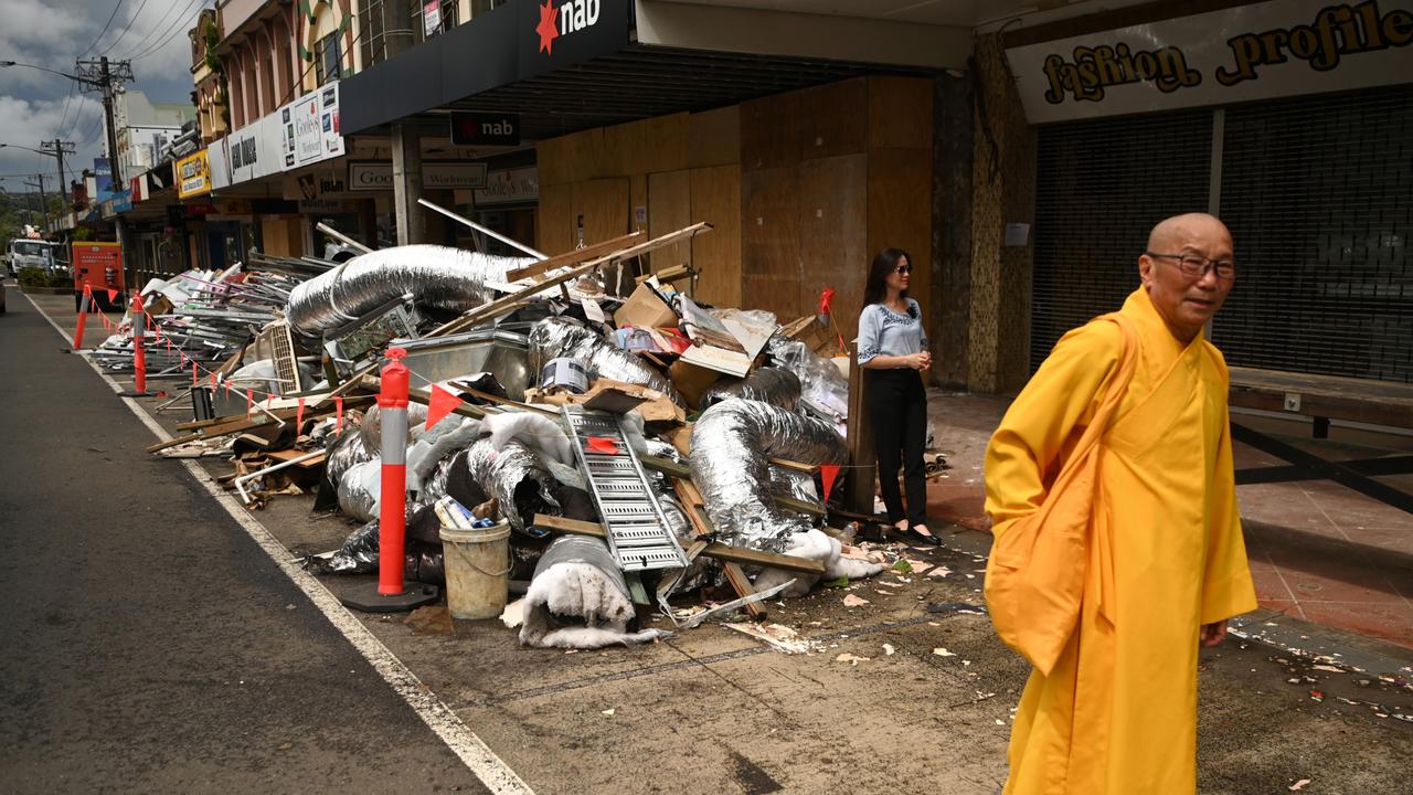 A Buddhist monk from the Unified Vietnamese Buddhist Congregation of Australia and New Zealand, part of a group visiting flood affected areas and donating money to victims, walks past a pile of debris in the city centre on March 29, 2022 in Lismore, Australia. Evacuation orders have been issued for towns across the NSW Northern Rivers region, with flash flooding expected as heavy rainfall continues. It is the second major flood event for the region this month. (Photo by Dan Peled/Getty Images)