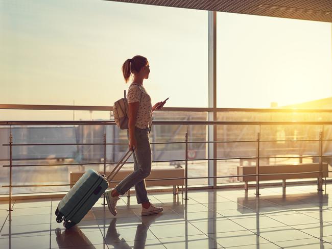 young woman goes  at airport  at window  with a suitcase waiting for  plane. Picture: iStockDoc Holiday