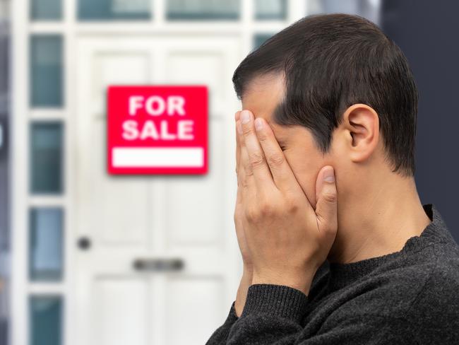 Man extremely depressed and sad about losing his house key and seeing a for sale sign, real estate concept; first home buyer generic sad, stressed