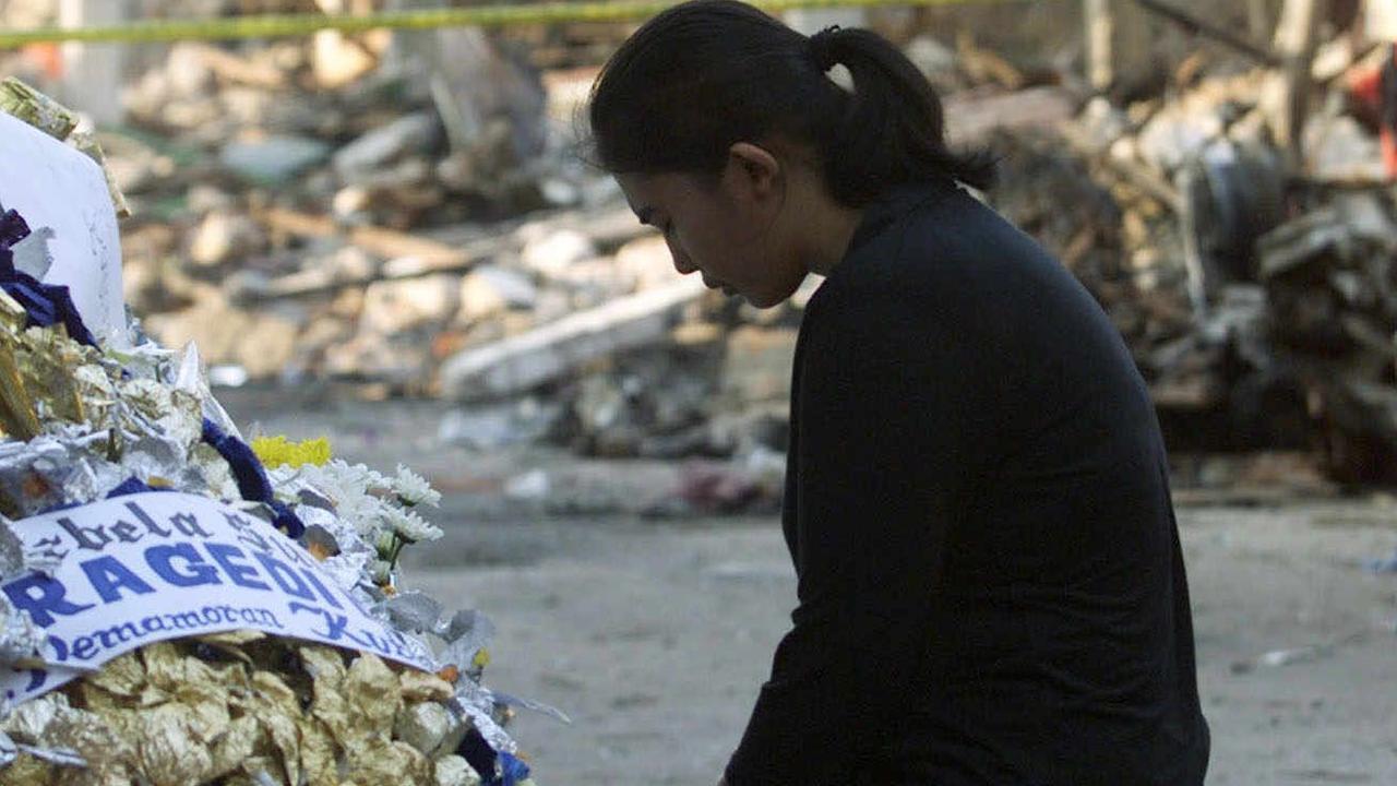 A woman prays at the site of one of the bomb blasts after the Bali bombings that occurred on this day in 2002.