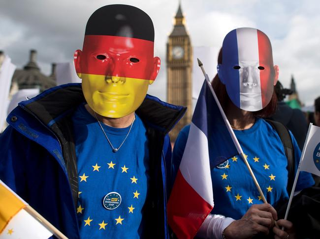 (FILES) This file photo taken on February 20, 2017 shows protesters wearing German and French flag face masks pose for a photograph during a "Flag Mob" demonstration in Parliament Square in central London on February 20, 2017, part of a national day of action in support of migrants in the UK.  EU migrants said on June 23 that far from being "generous", Prime Minister Theresa May's offer for their post-Brexit residency was niggardly and left them prey to the whims of British lawmakers. One year ago today on June 23, 2016 Britain voted to leave the European Union. / AFP PHOTO / Justin TALLIS