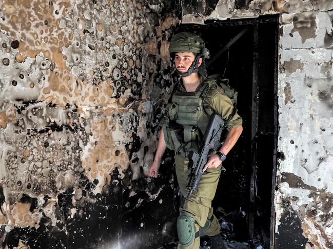 An Israeli army soldier walks through a burnt building during a patrol in kibbutz Kfar Aza in southern Israel near the Gaza Strip on October 18, 2023. Thousands of people, both Israeli and Palestinians have died since October 7, 2023, after Palestinian Hamas militants based in the Gaza Strip, entered southern Israel in a surprise attack leading Israel to declare war on Hamas in Gaza on October 8. (Photo by JACK GUEZ / AFP)