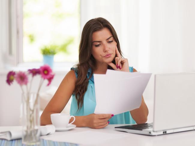 A woman with her computer and bank statements sitting at a desk. She is also analysing her superannuation statement. Picture: iStock.