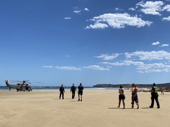 Two people with their arms in slings are escorted to an air ambulance.