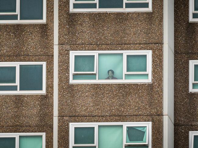 A lone woman is seen looking out the window of her apartment at the North Melbourne Public housing flats. Asanka Ratnayake/Getty Images