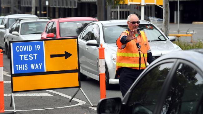 A traffic controller manages cars queueing at a drive-through COVID-19 testing sitein Melbourne, Picture: AFP.